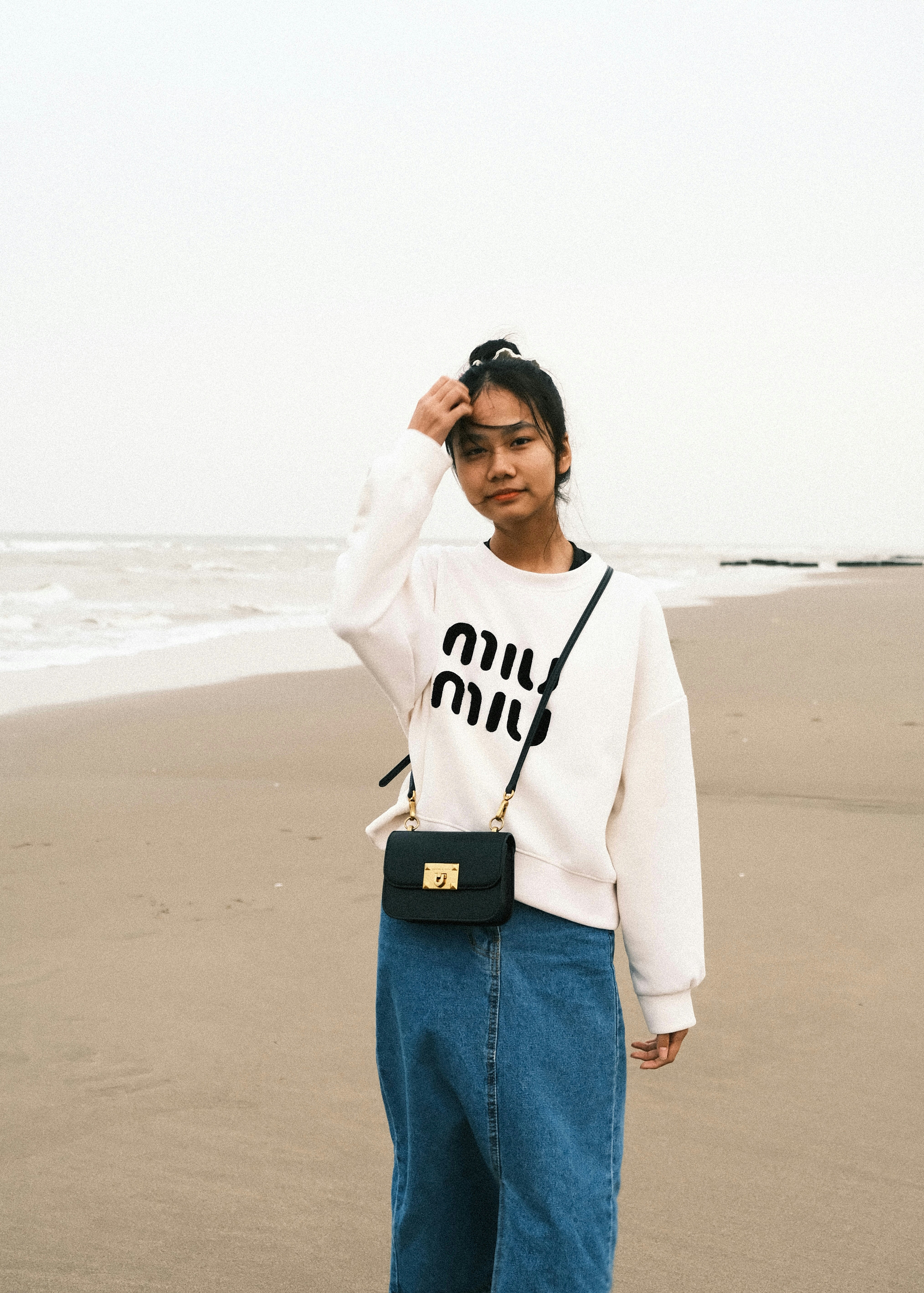 A woman standing on top of a beach next to the ocean photo – Free Pants ...