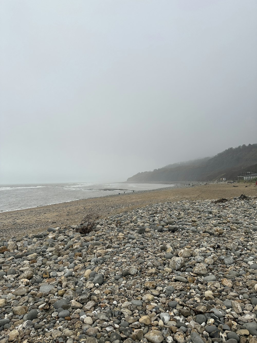 a bench sitting on top of a rocky beach next to the ocean