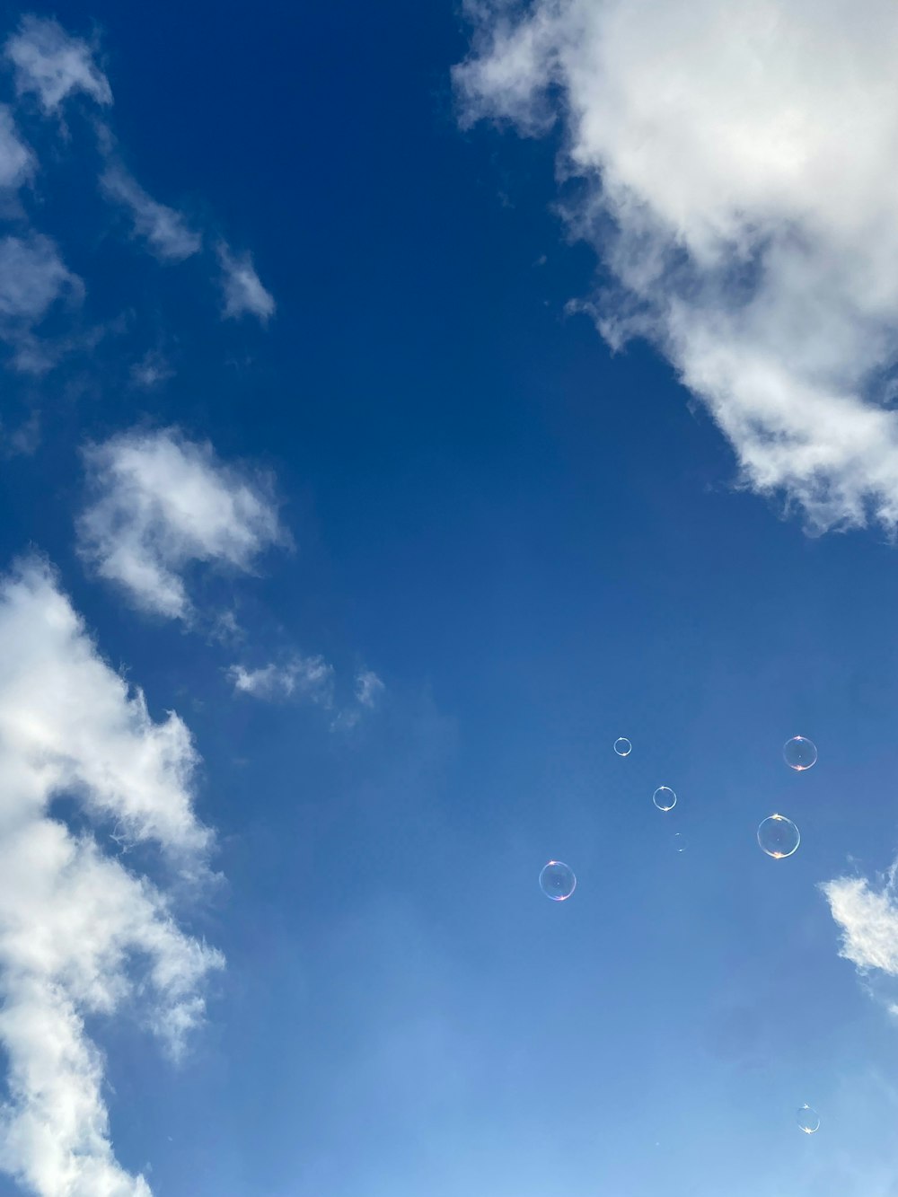a clear blue sky with bubbles floating in the air