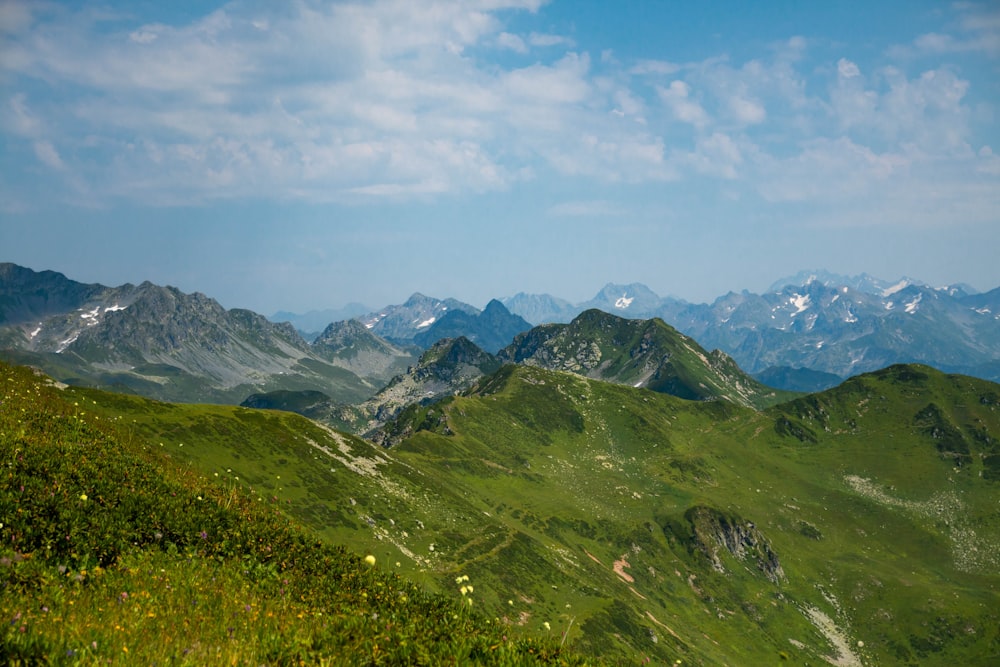 a view of a mountain range with green grass and mountains in the background