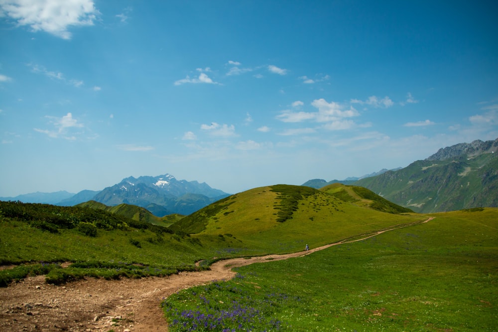 a dirt path going through a lush green valley