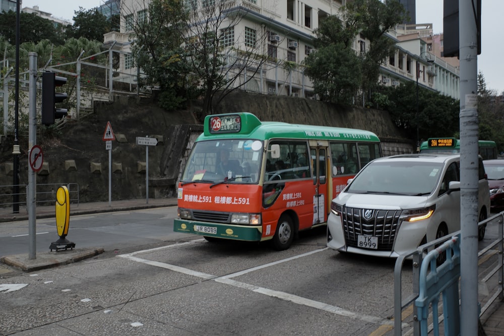 a red and green bus driving down a street