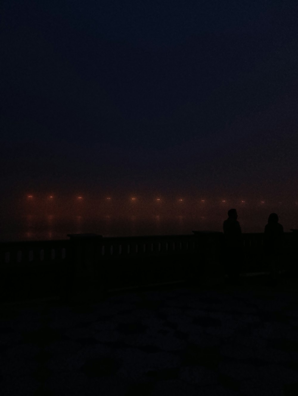 a couple of people sitting on a bench at night