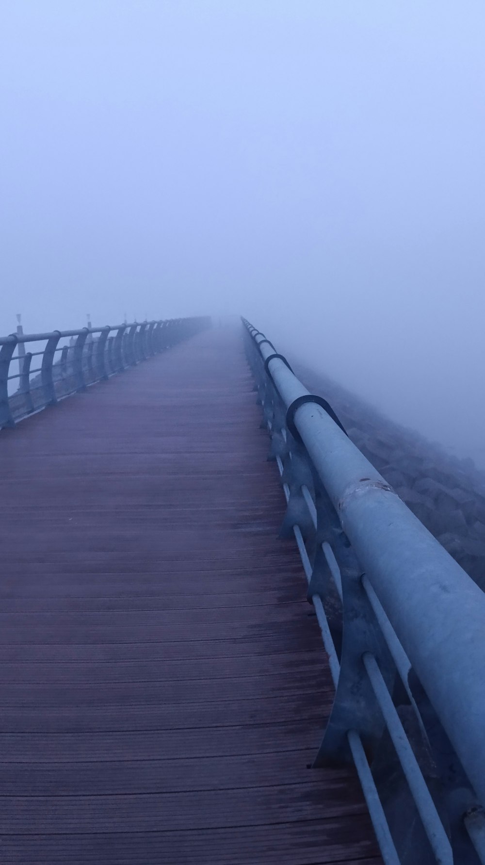 a wooden bridge in the middle of a foggy day