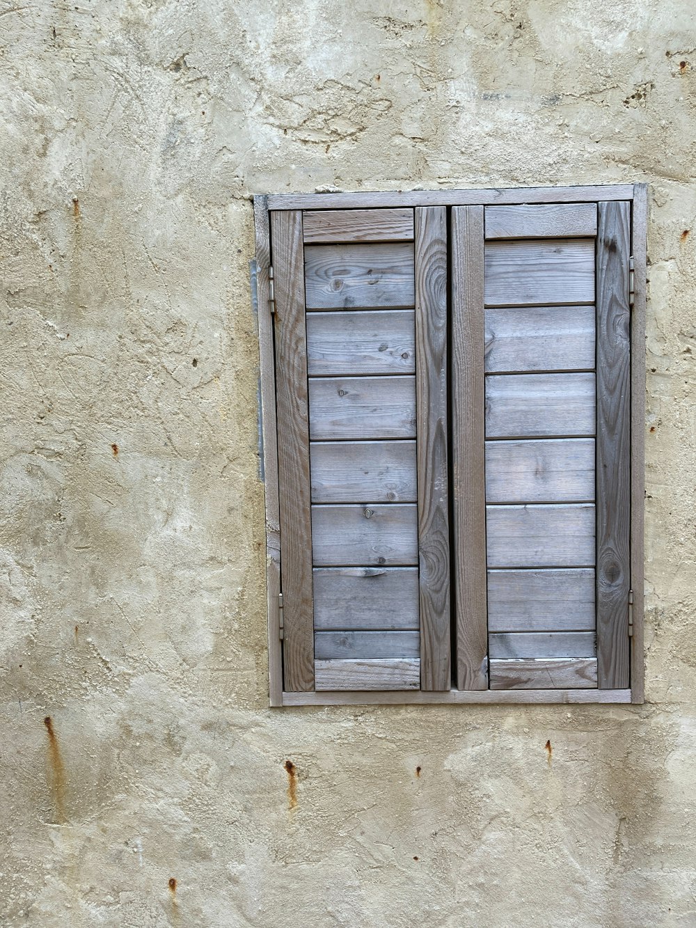 a window with wooden shutters on a stucco wall