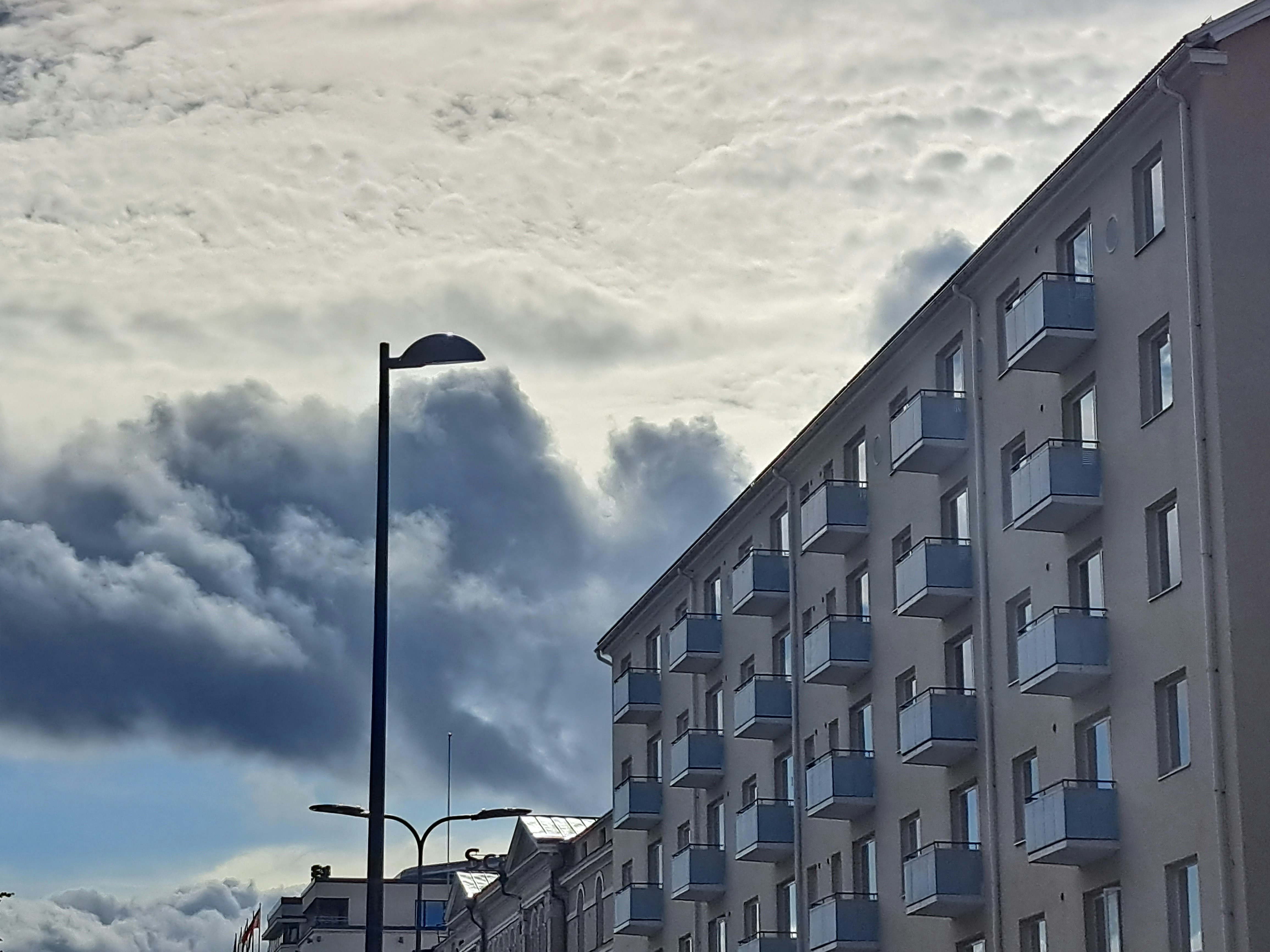 a tall building sitting next to a tall building under a cloudy sky