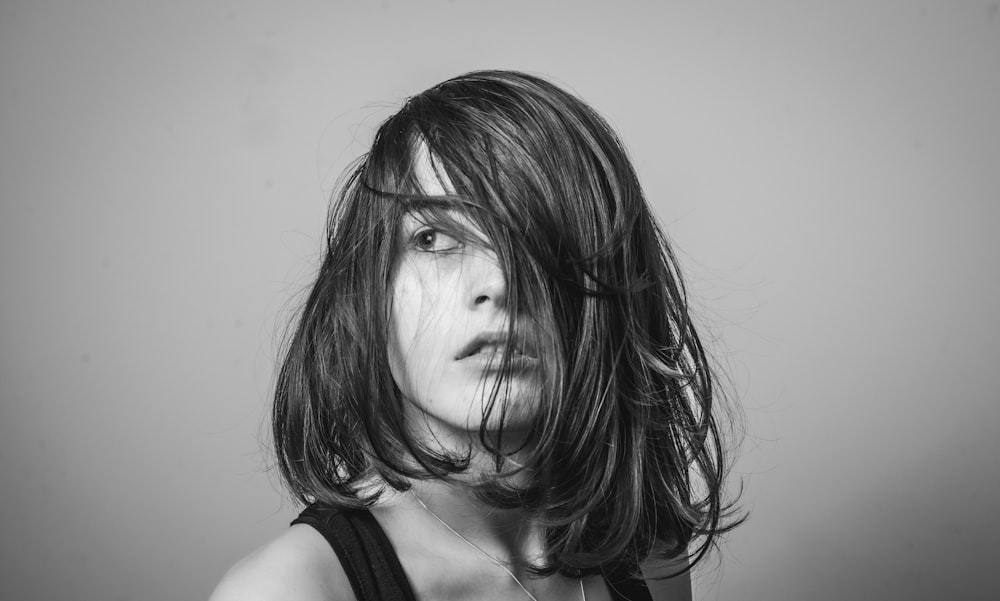 a black and white photo of a woman with her hair blowing in the wind