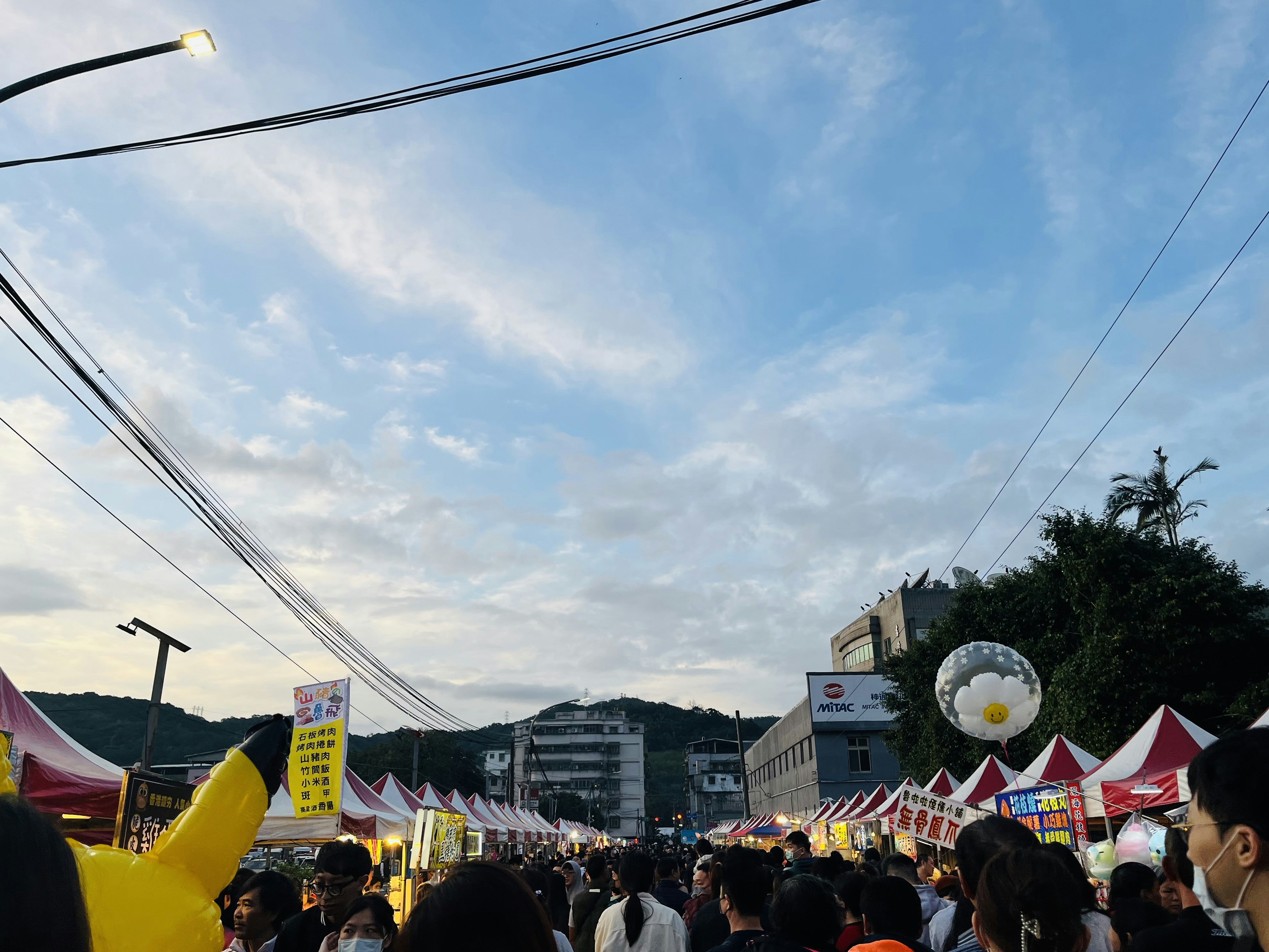 a crowd of people walking down a street next to tents