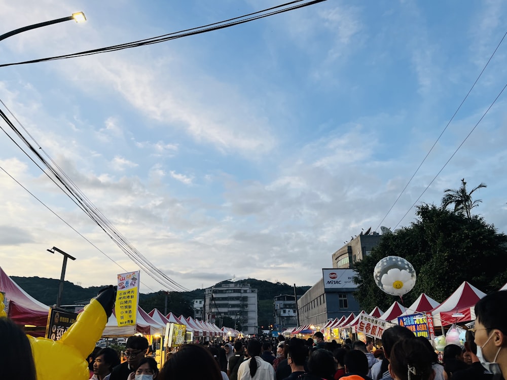 a crowd of people walking down a street next to tents