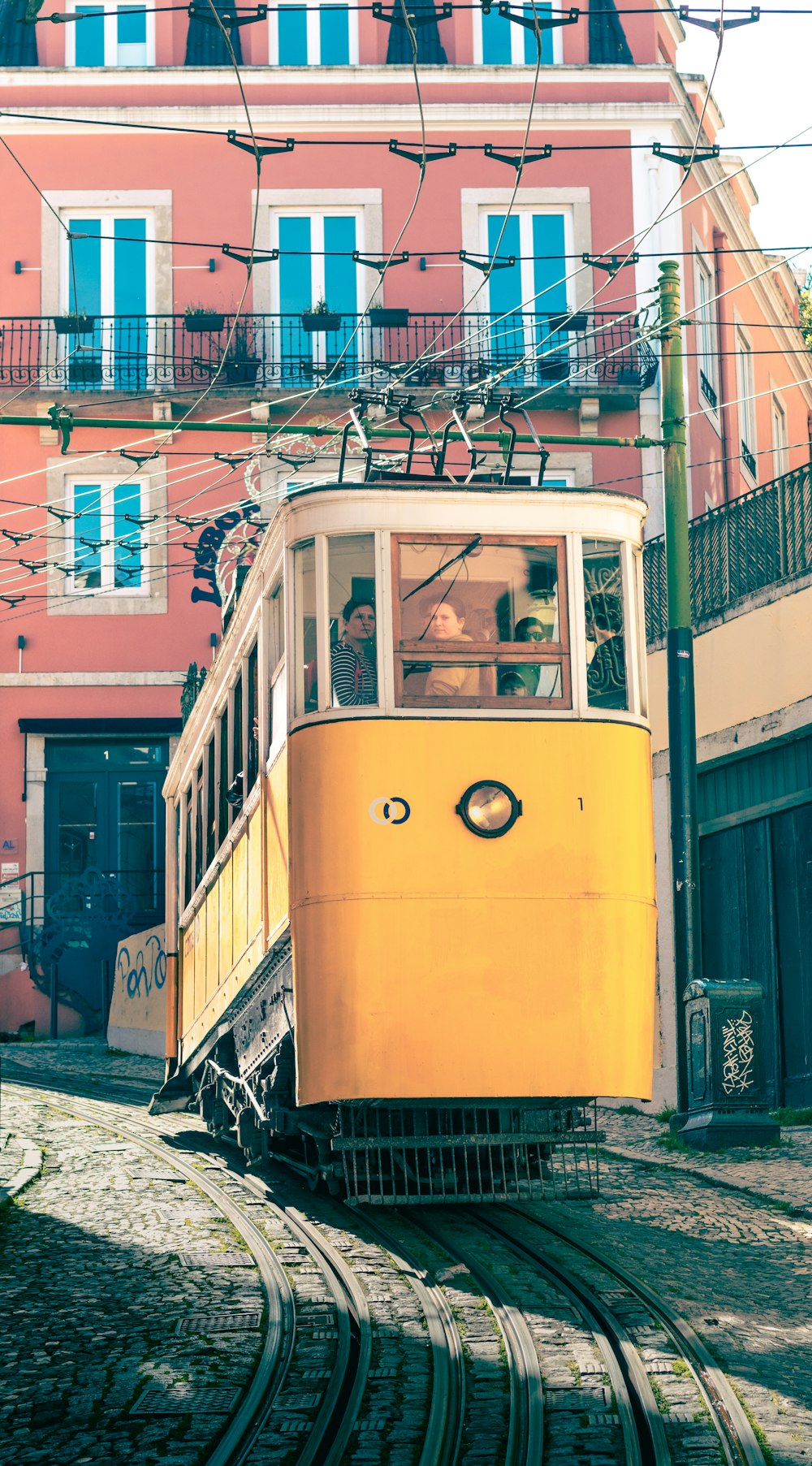 a yellow trolley car traveling down a street next to a tall building