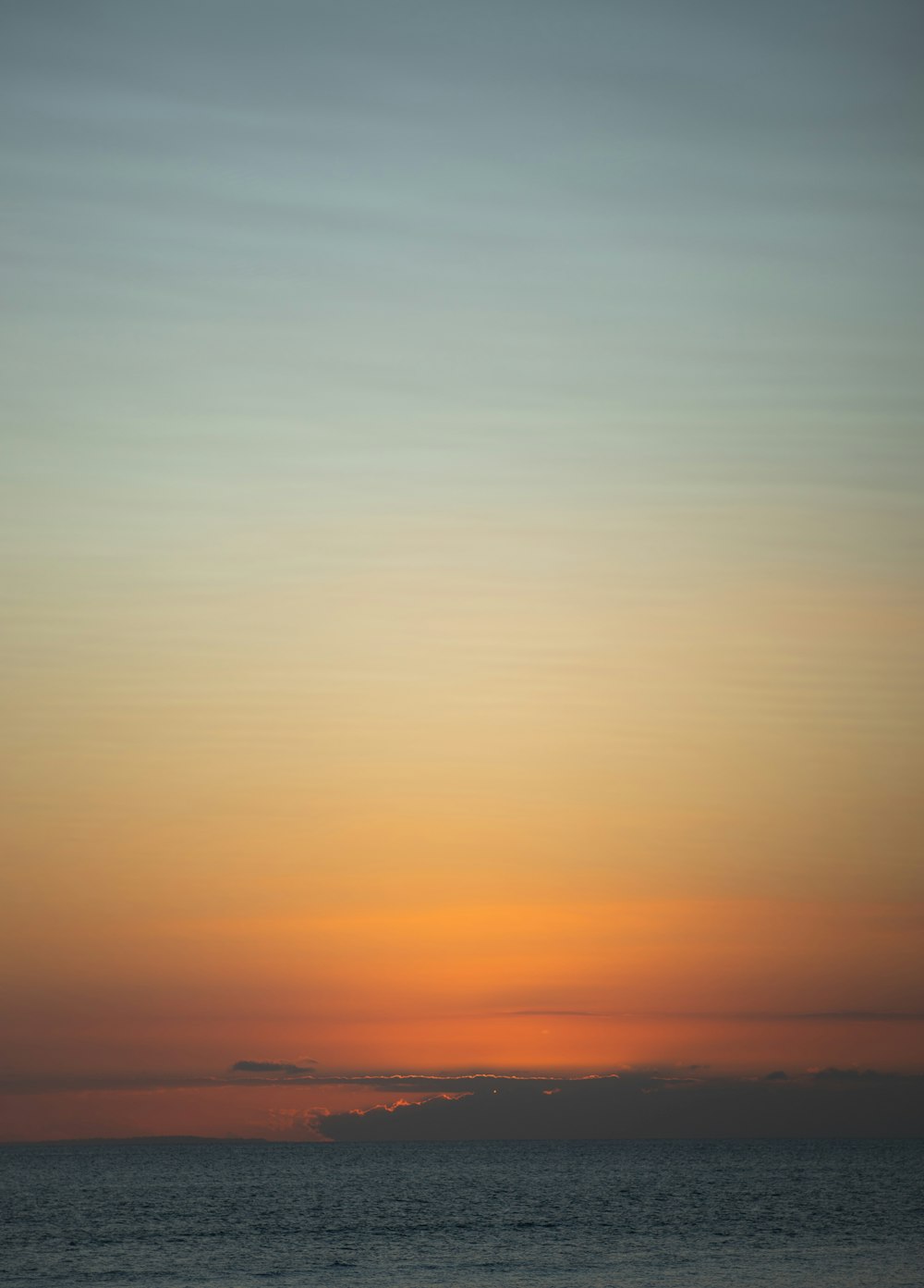 the sun is setting over the ocean on a cloudy day