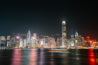 a city skyline at night with lights reflecting off the water