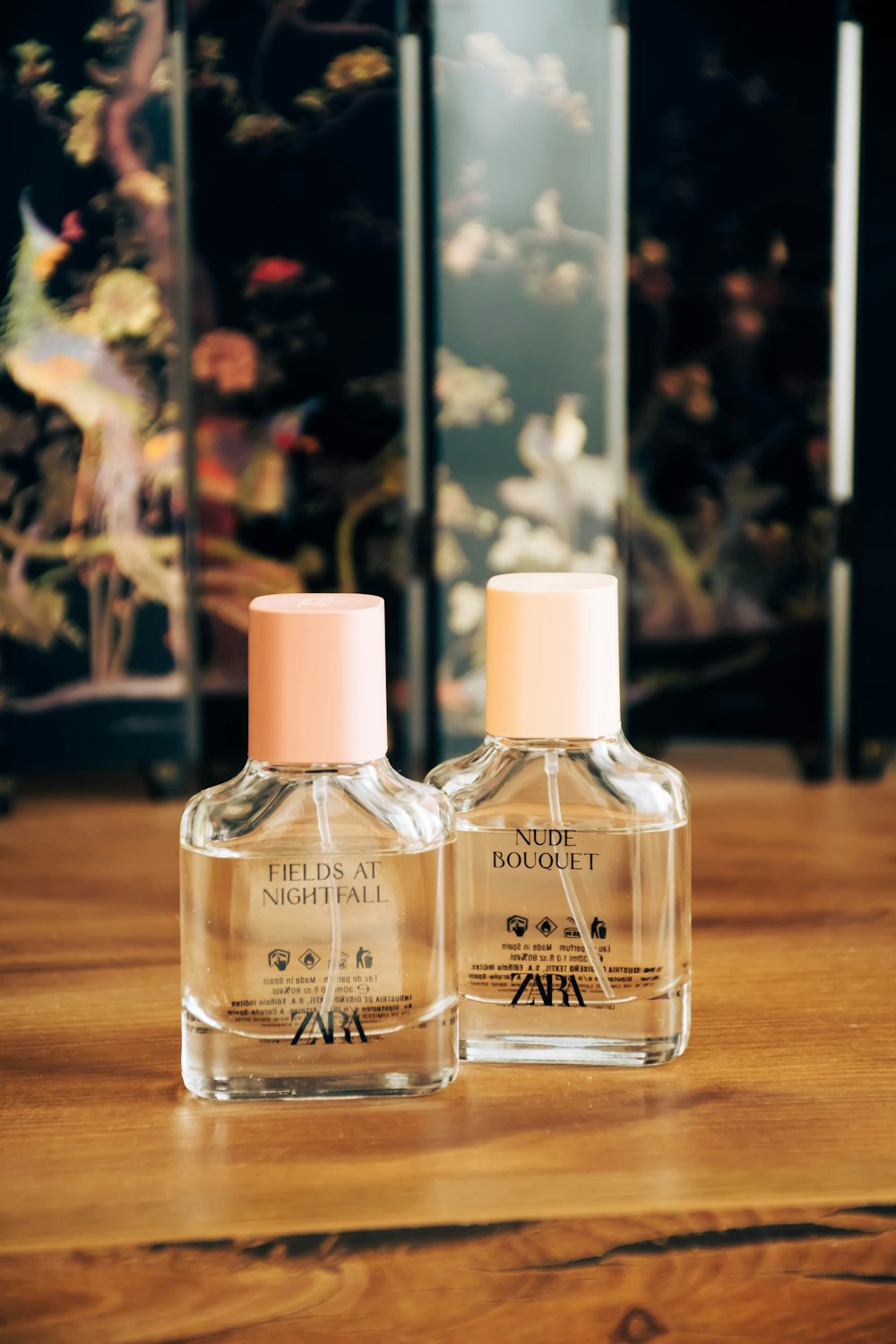 two bottles of perfume sitting on top of a wooden table