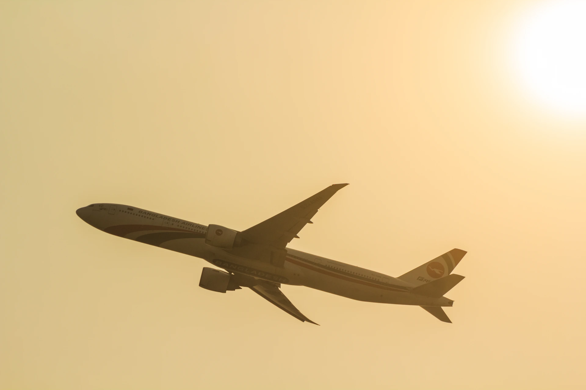 a large jetliner flying through a yellow sky