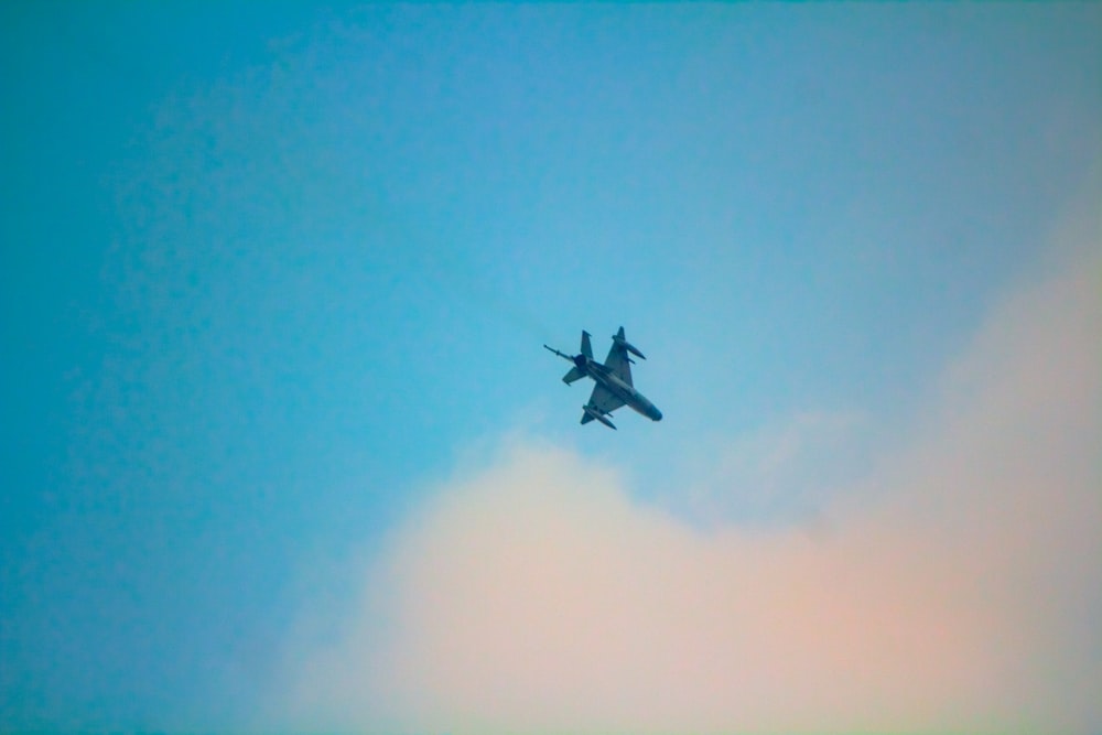 a fighter jet flying through a blue sky