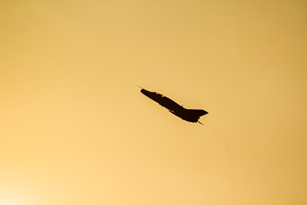 an airplane flying in the sky at sunset