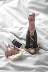 a bottle of wine and a bottle of perfume on a bed