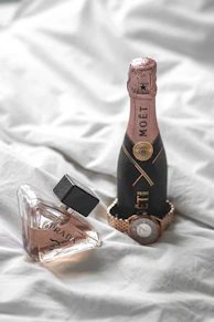 a bottle of wine and a bottle of perfume on a bed