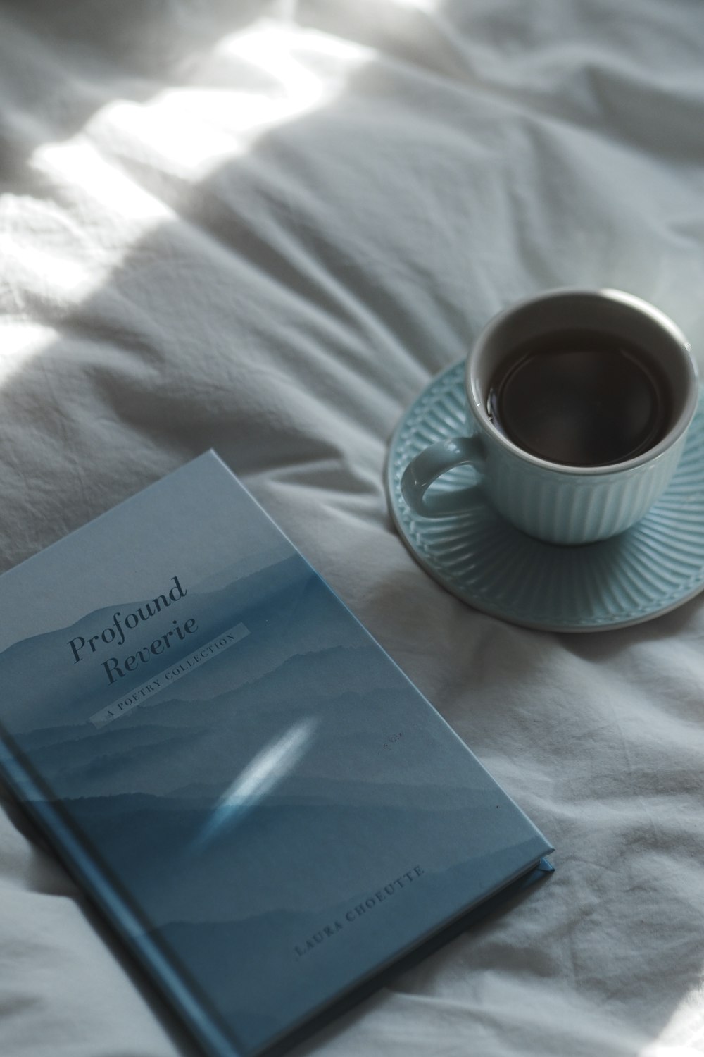 a cup of coffee and a book on a bed