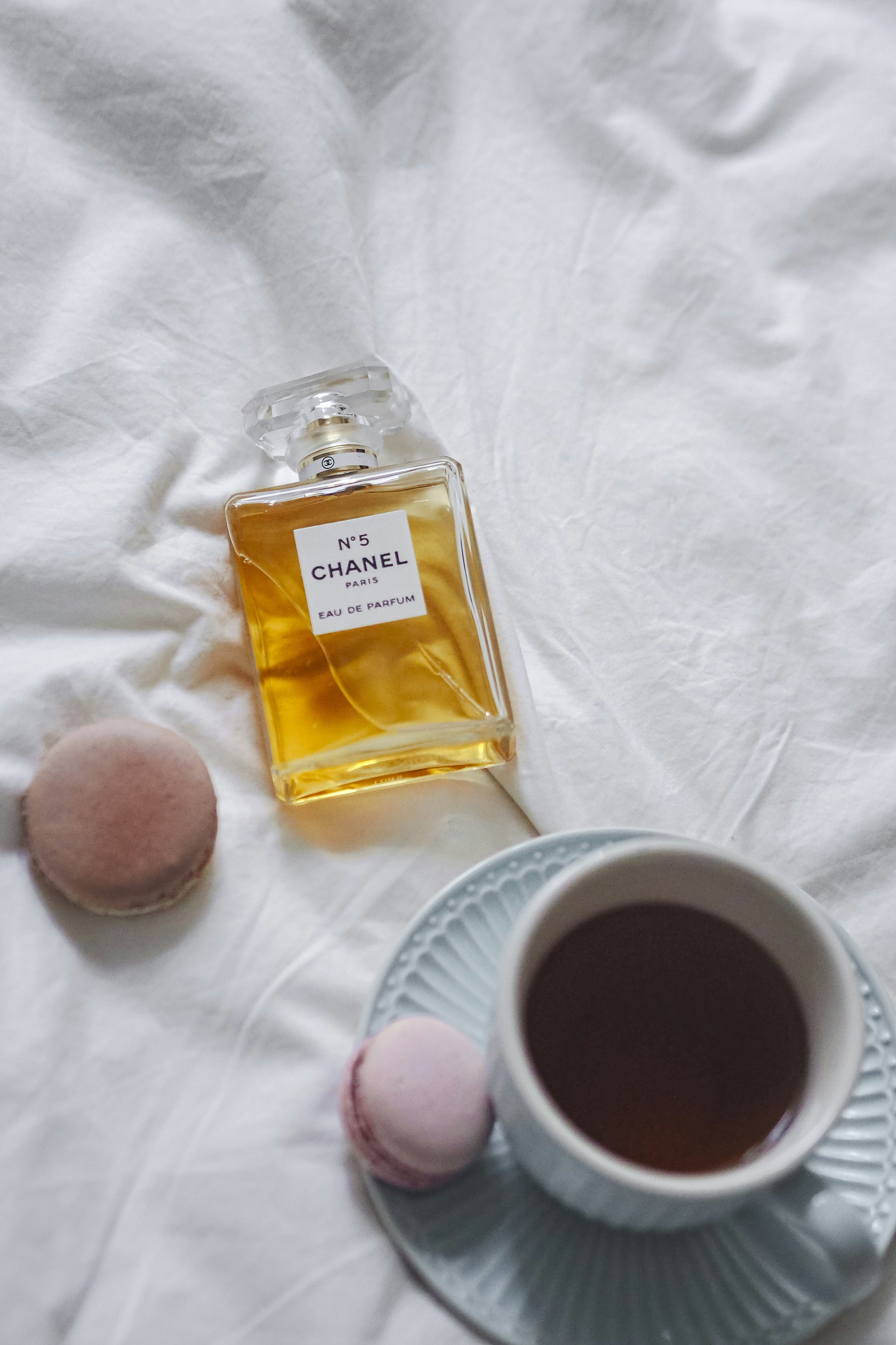 a cup of coffee next to a bottle of chanel