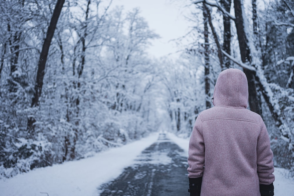 a person in a pink jacket walking down a snow covered road