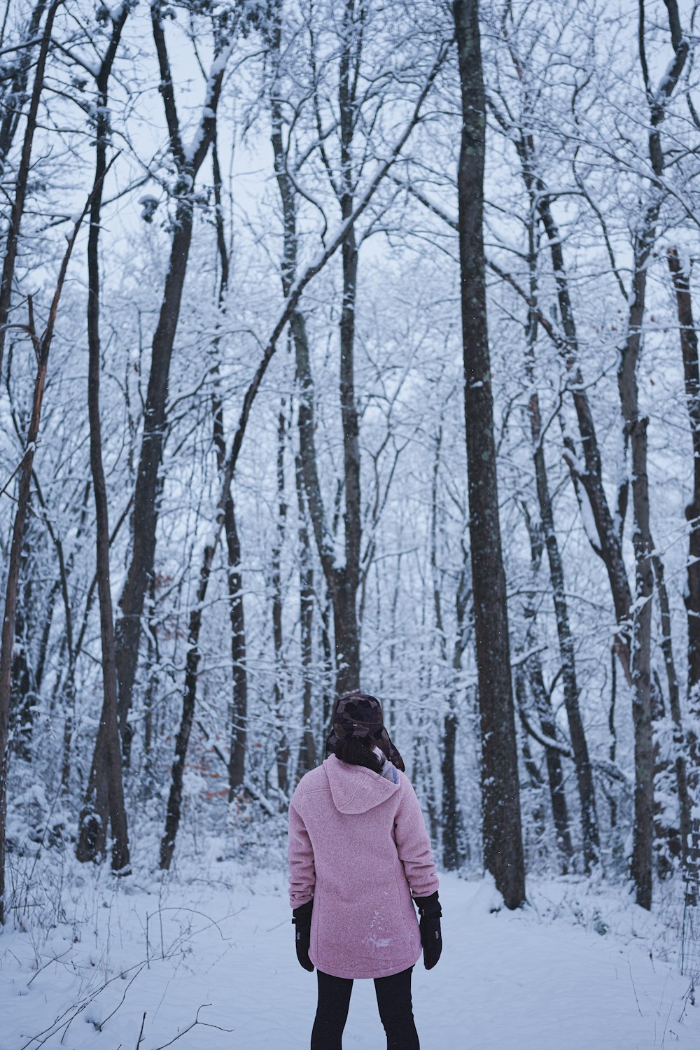 a woman in a pink coat standing in the snow
