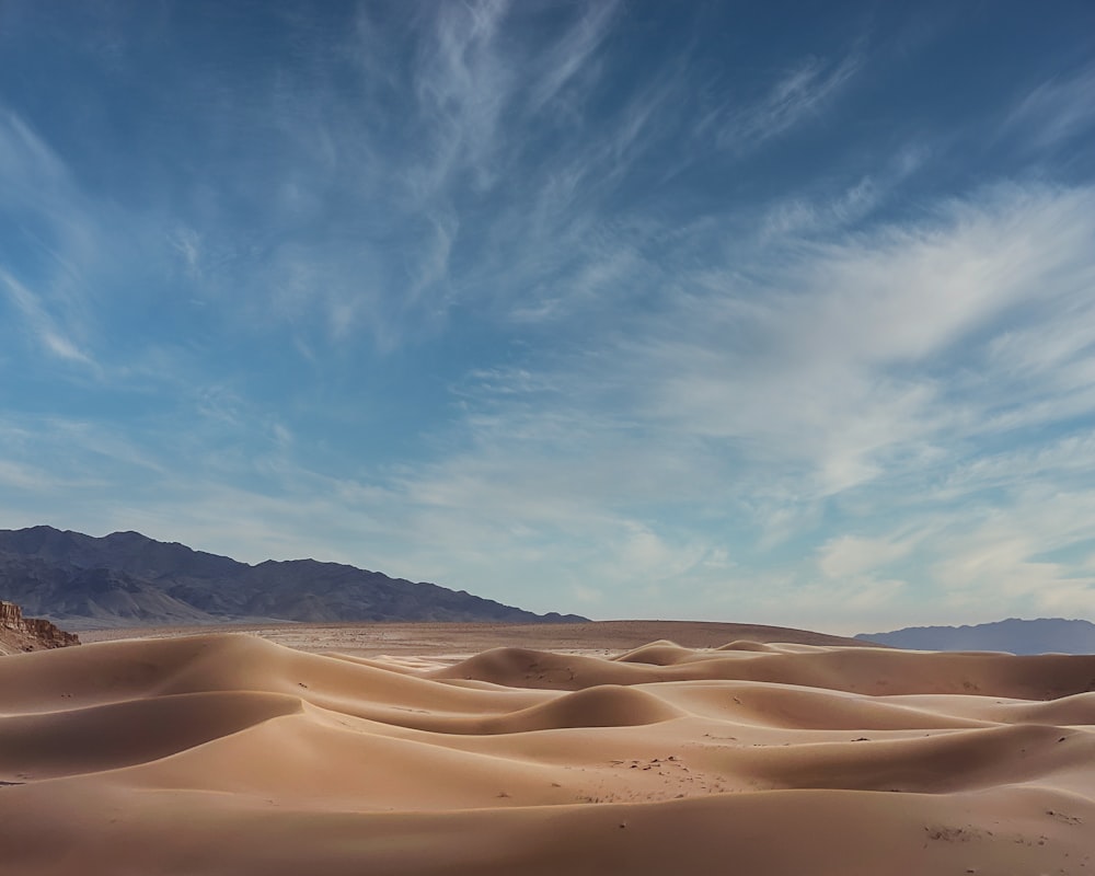 a desert landscape with sand dunes and mountains in the background