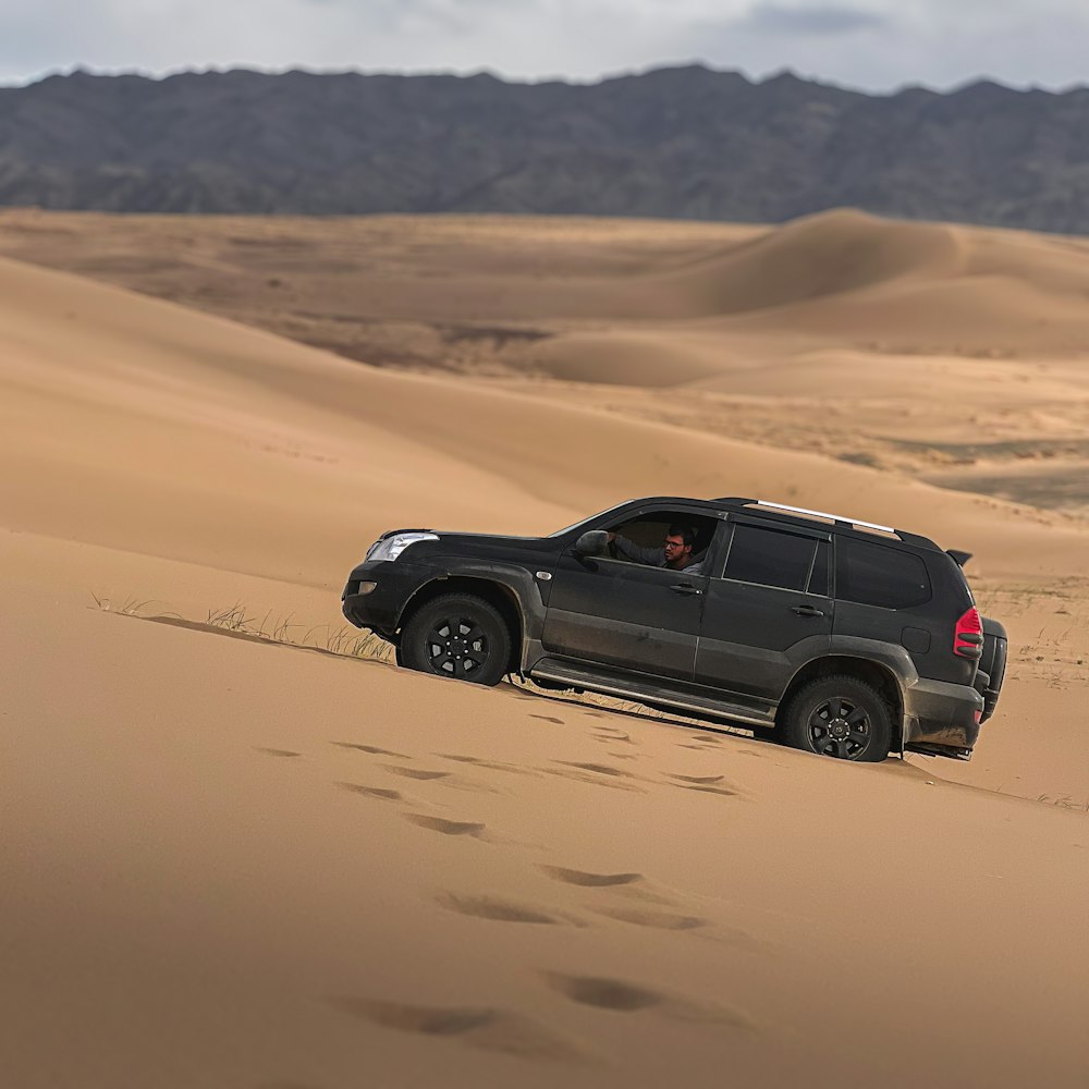 a suv driving through the desert in the sand