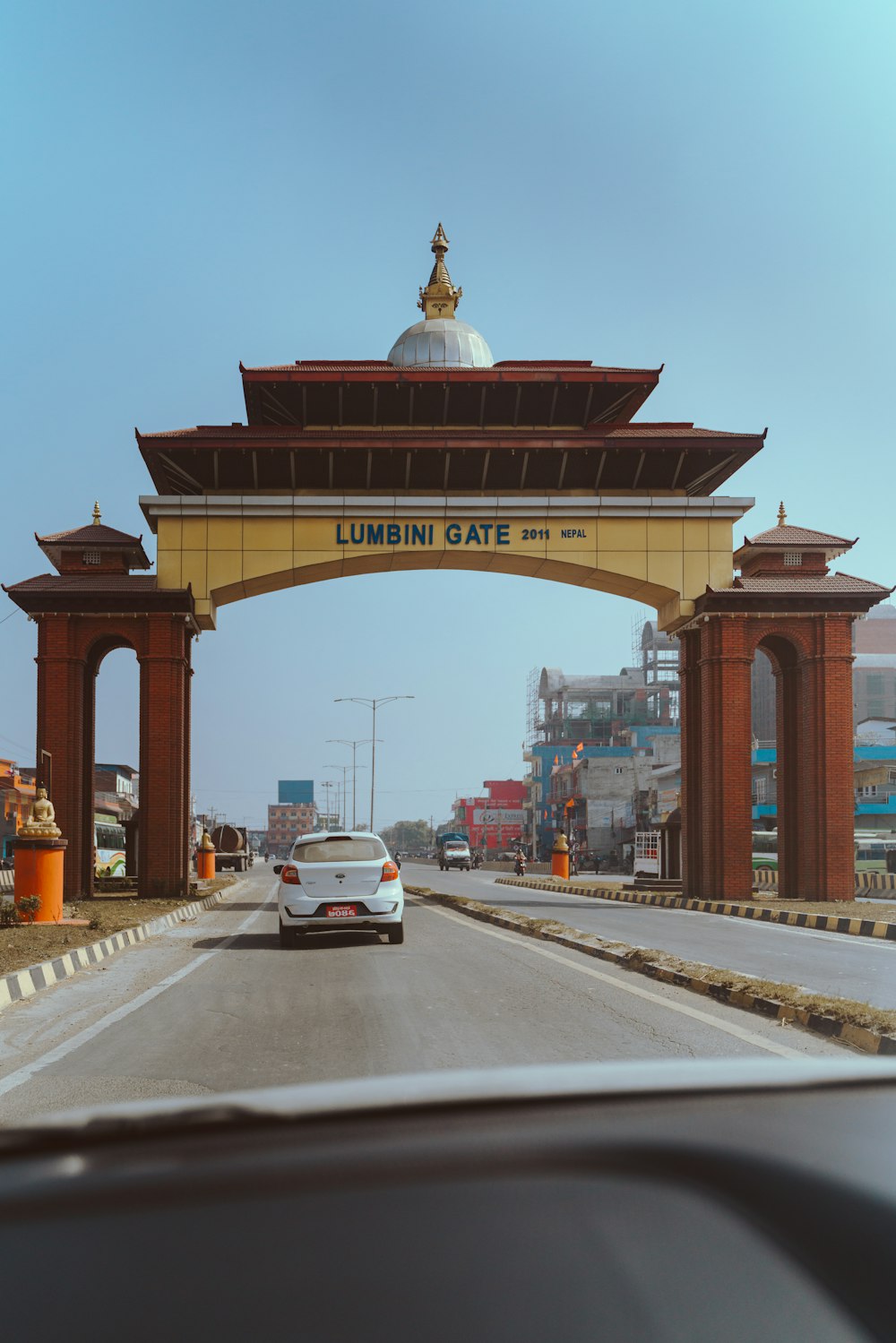 a car driving under a large arch on a road