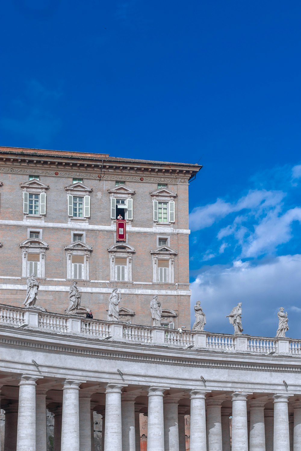 a building with columns and a clock tower in the background