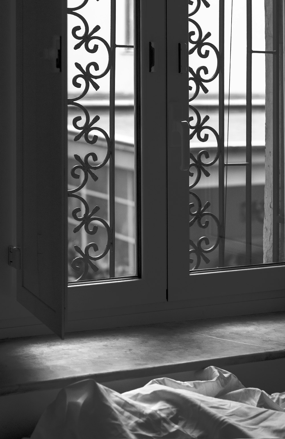 a black and white photo of a window and a bed