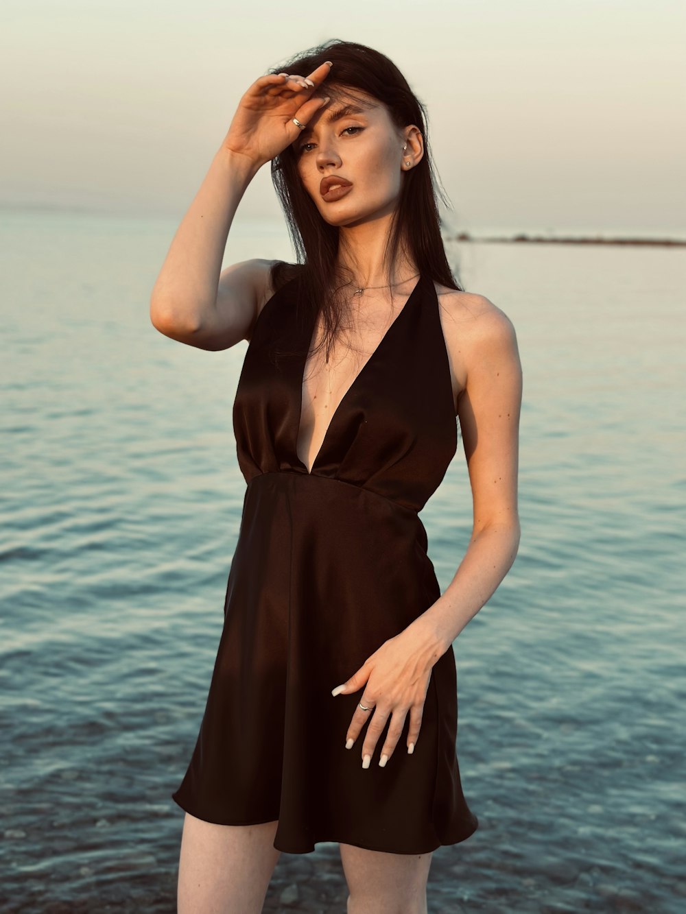 a woman in a black dress standing by the water