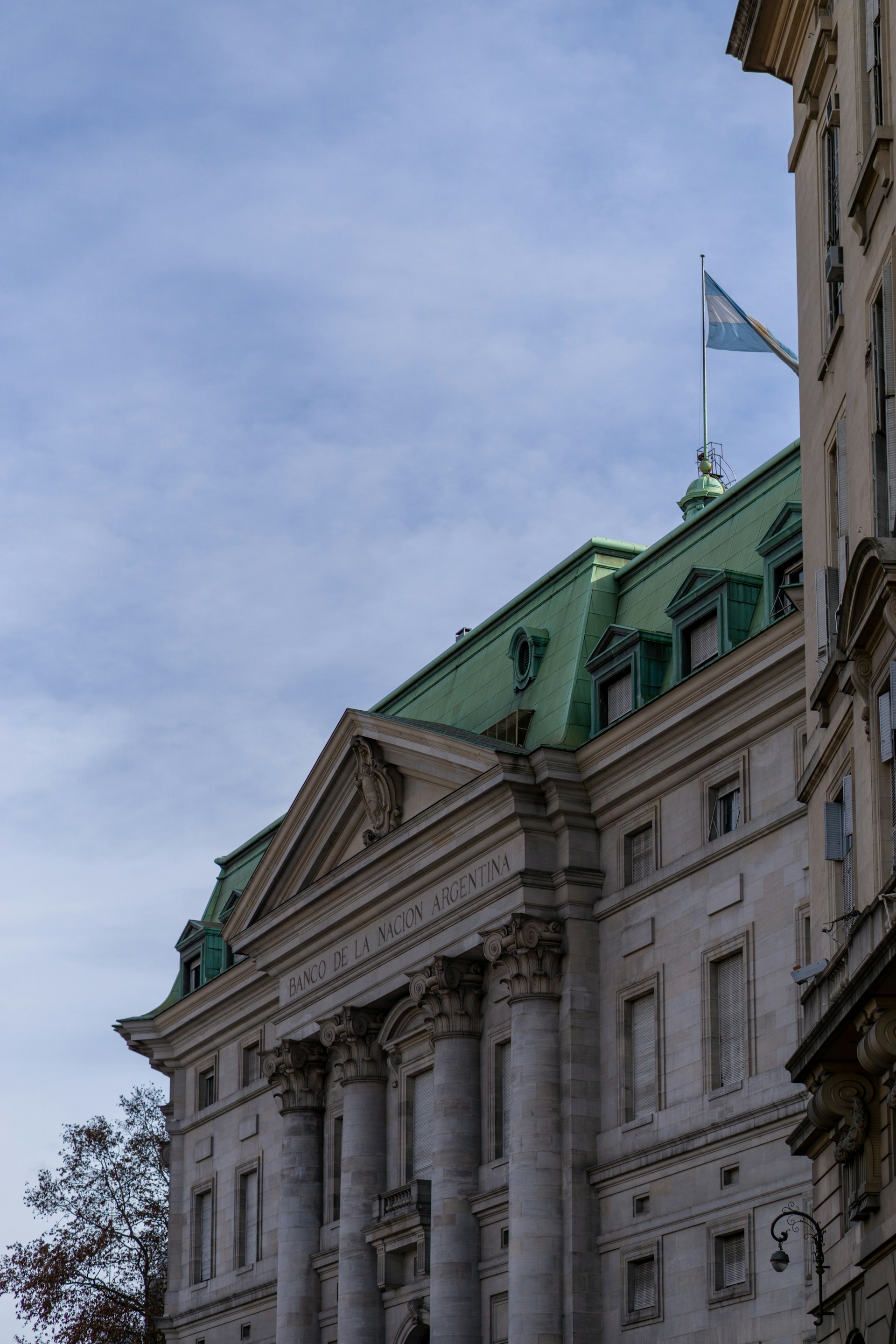 a tall building with a green roof and a flag on top