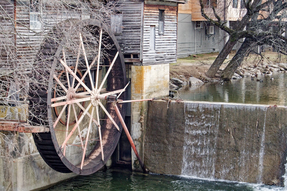 a water wheel sitting on top of a river next to a building