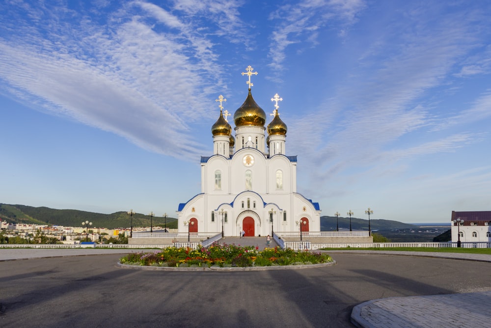 a large white church with gold domes on a sunny day