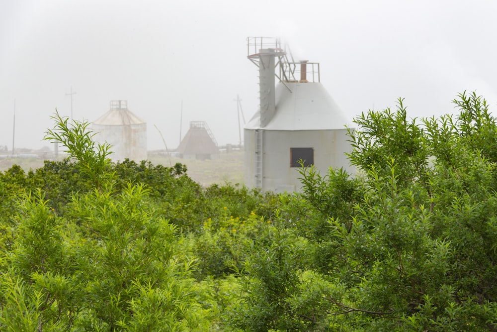 a white building surrounded by trees and fog