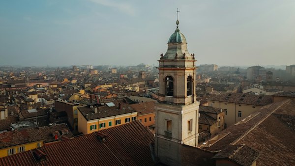 A tall tower with a clock on top of a building — Modena, Italy