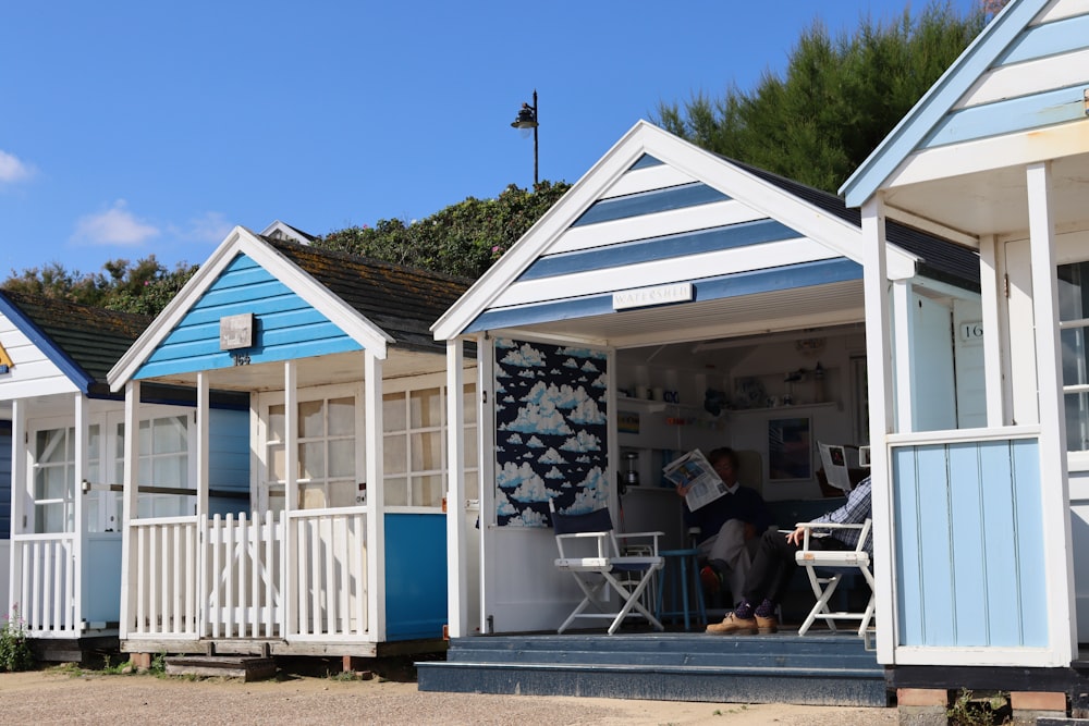 a row of beach huts with a man reading a newspaper
