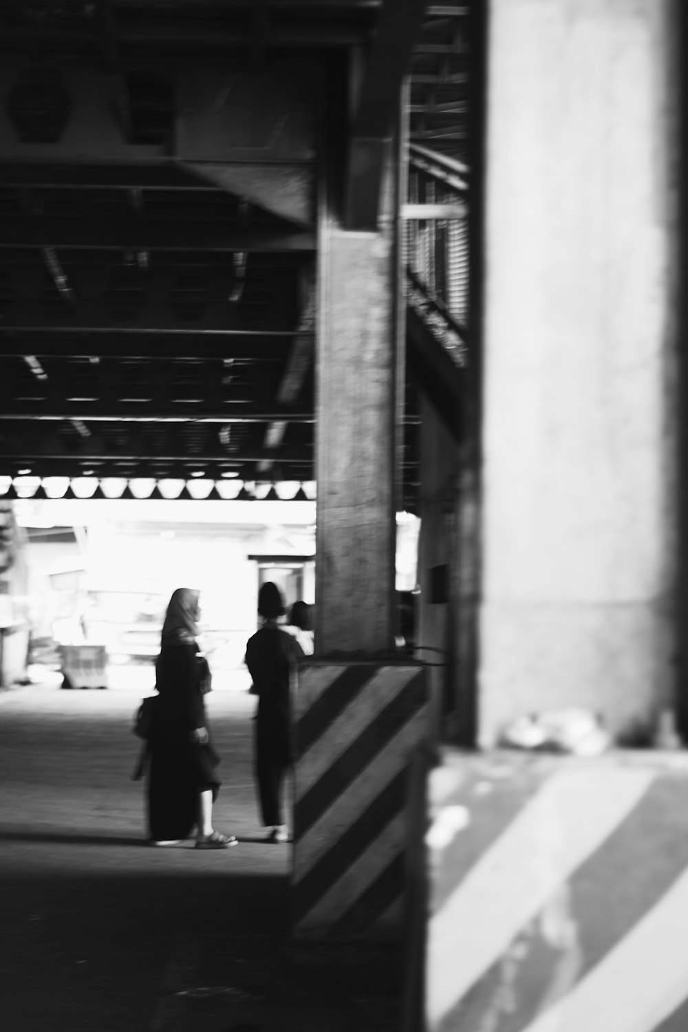 a black and white photo of two people under a bridge