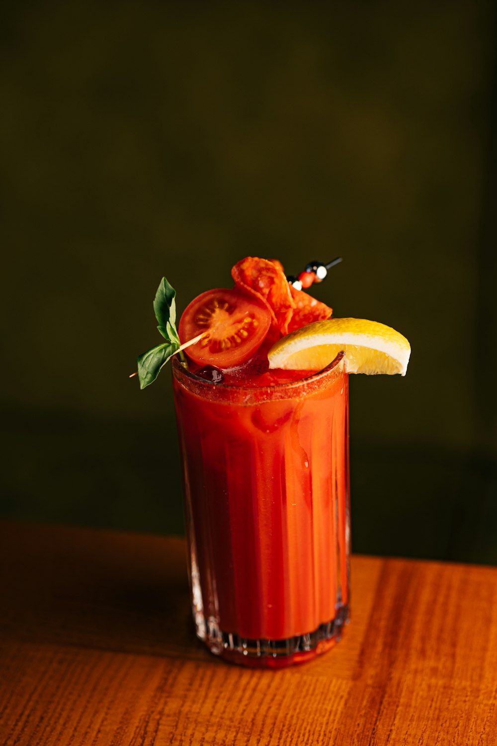 a bloody drink garnished with a slice of lemon and tomato