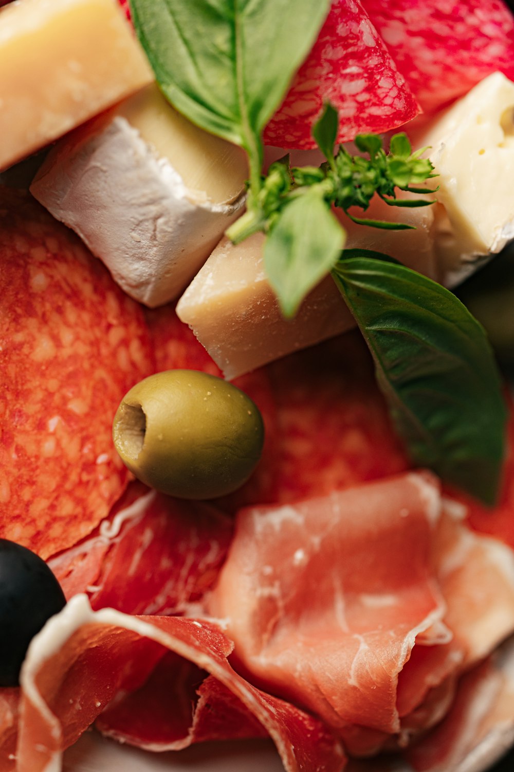 a plate of meats, cheeses, and olives