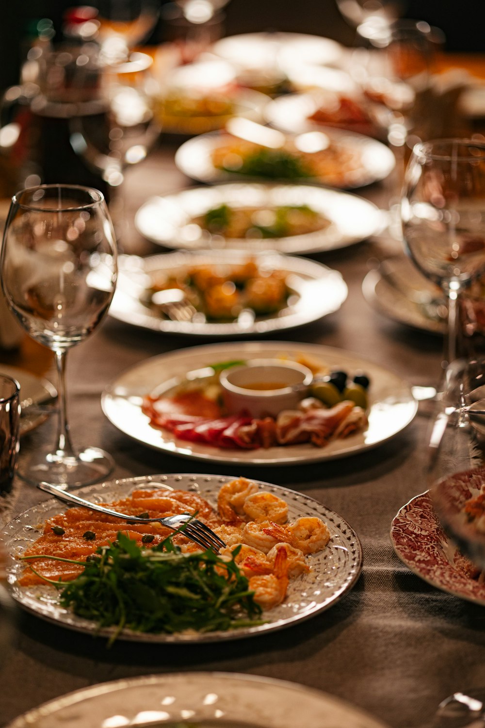 une longue table avec des assiettes de mets et de verres à vin