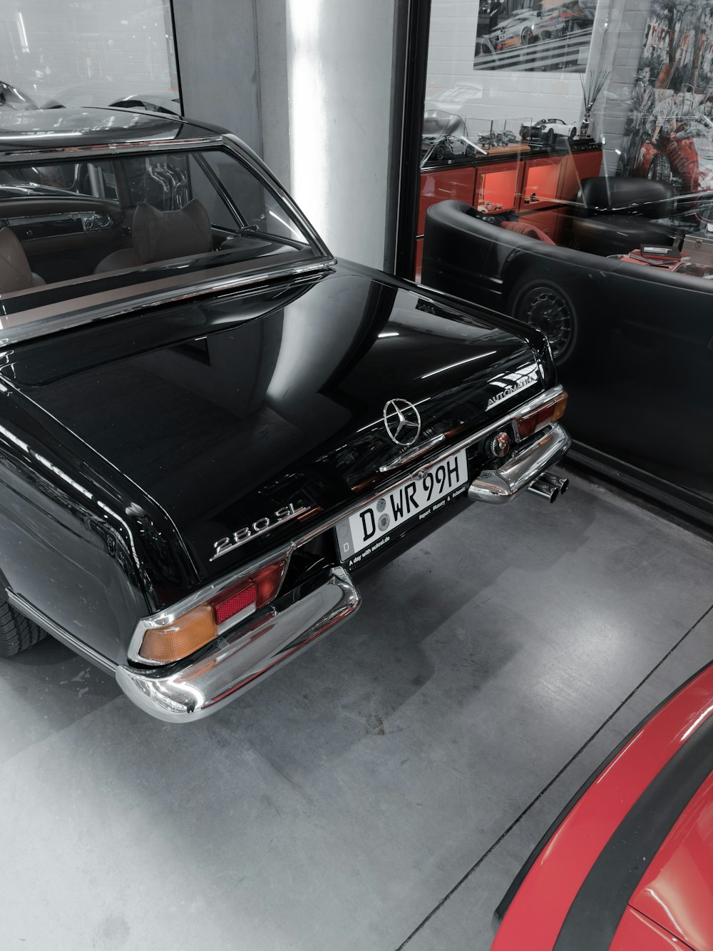 a black car parked in a garage next to a red car