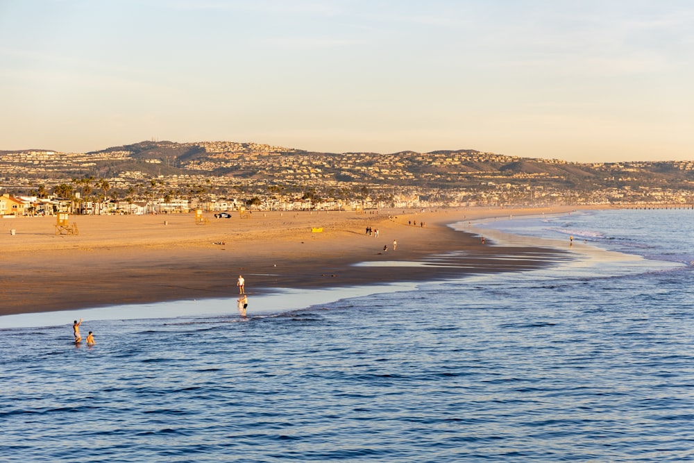 a beach with people walking on it and a hill in the background