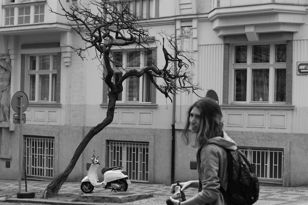 a woman walking down a street next to a tree