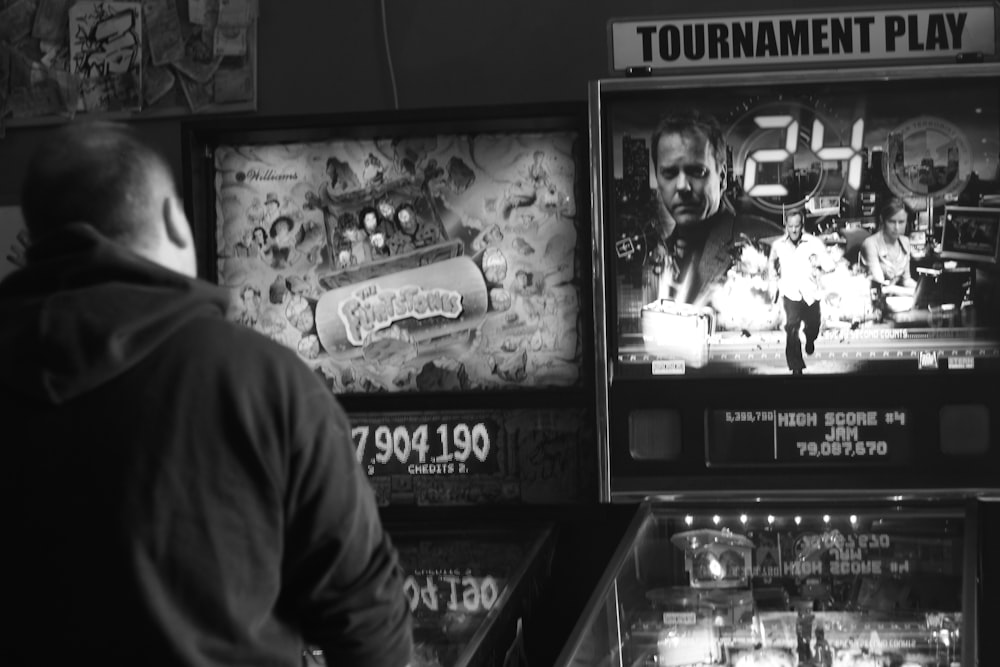 a man standing in front of a pinball machine