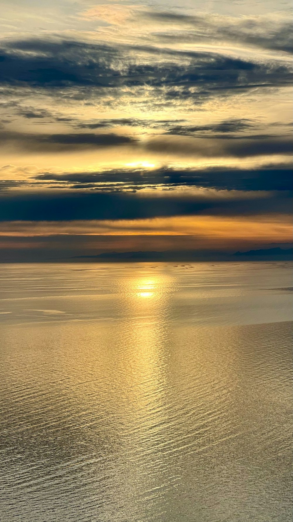 the sun is setting over the ocean on a cloudy day