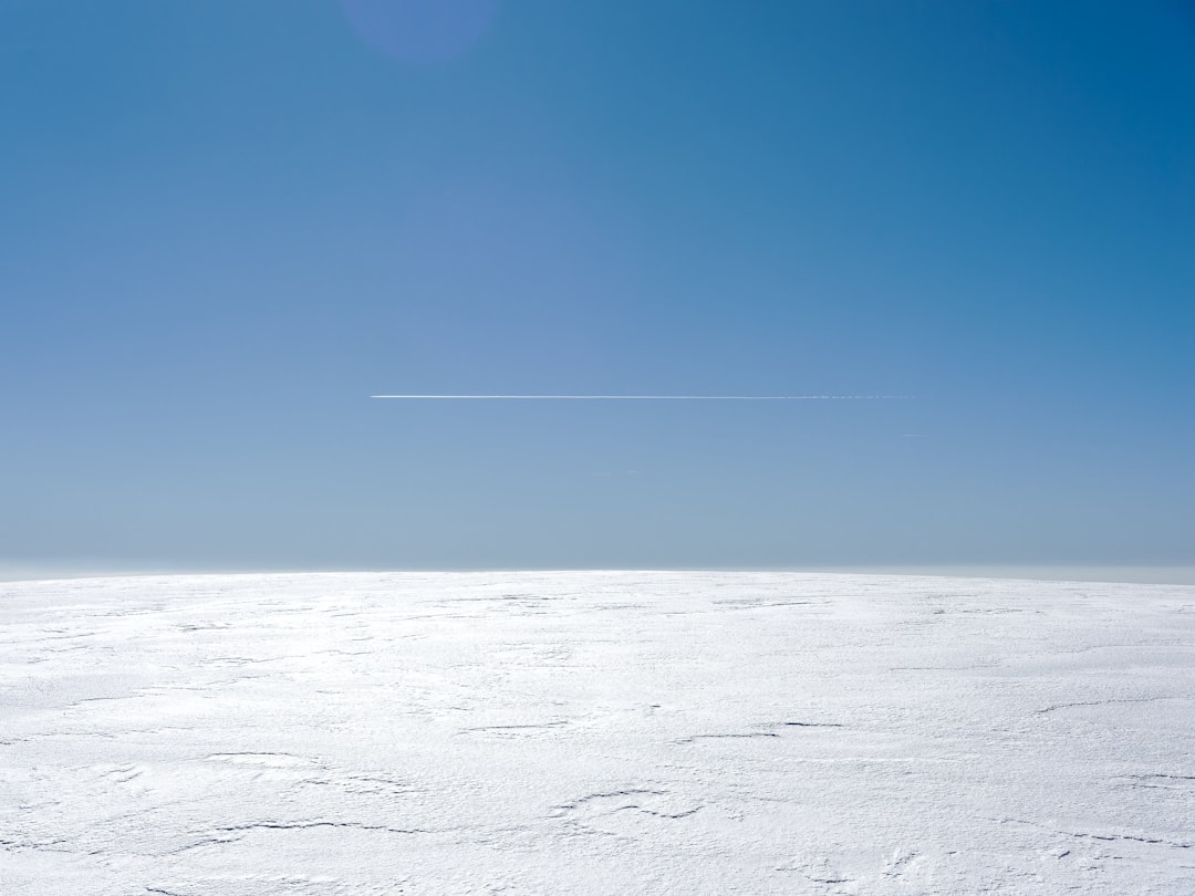 a plane flying over a snow covered field