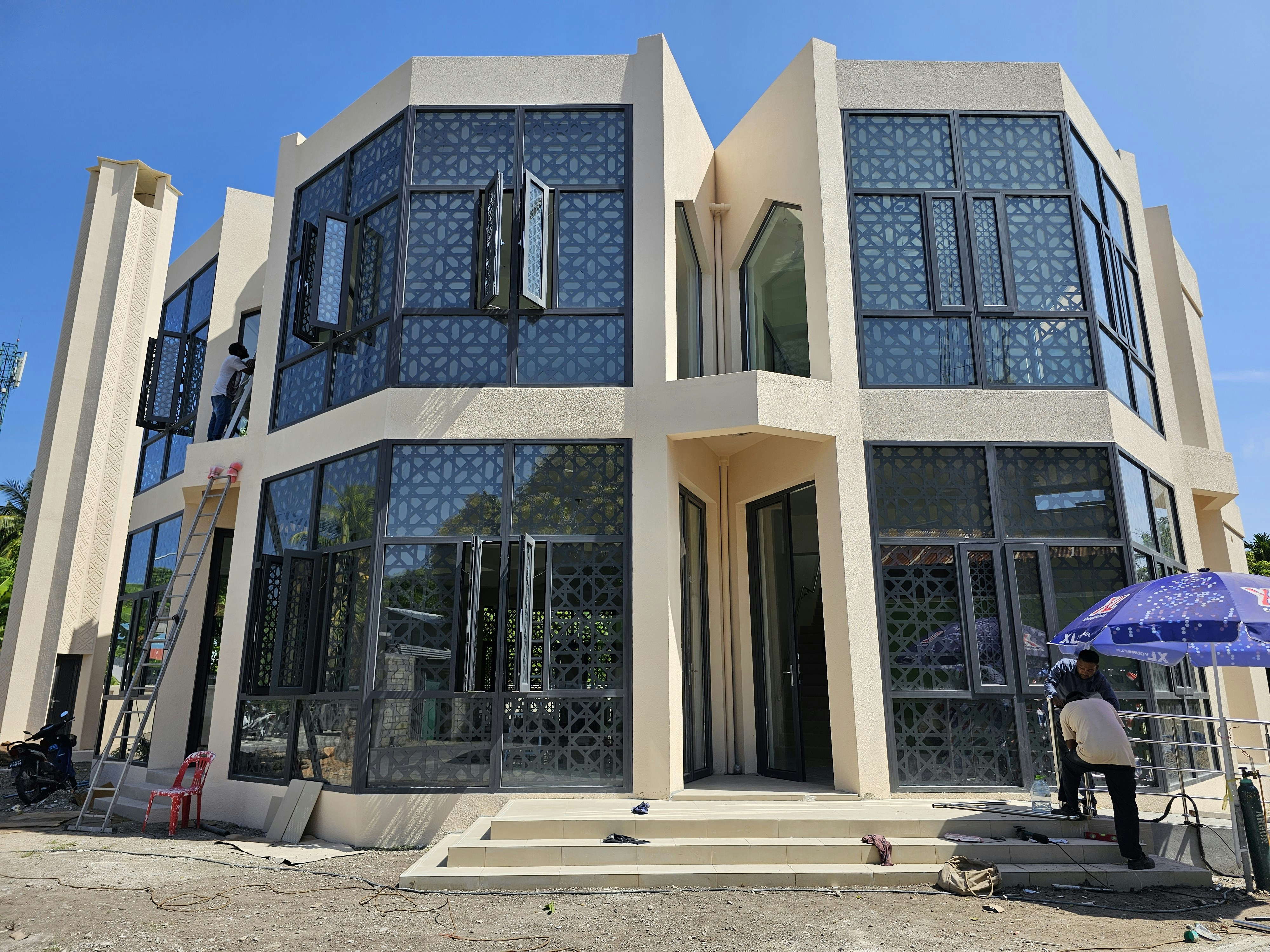 Des ouvriers du bâtiment installent des fenêtres sur un immeuble moderne à plusieurs étages.