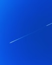 a jet flying through a blue sky with a contrail